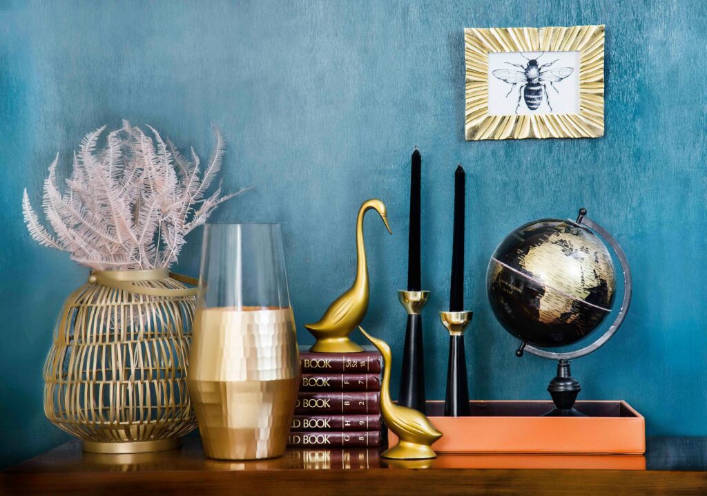 pexels photo 1099816 1099816 Stylish home decor arrangement including a globe, books, candles, and vases on a blue backdrop.